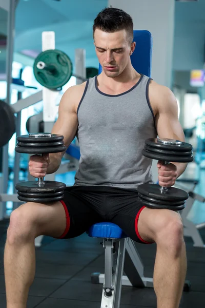 Мускулистый молодой человек делает тяжелые упражнения веса для бицепсов с D — стоковое фото