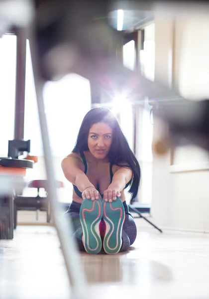 Jovem mulher fazendo exercícios de alongamento no chão no ginásio — Fotografia de Stock