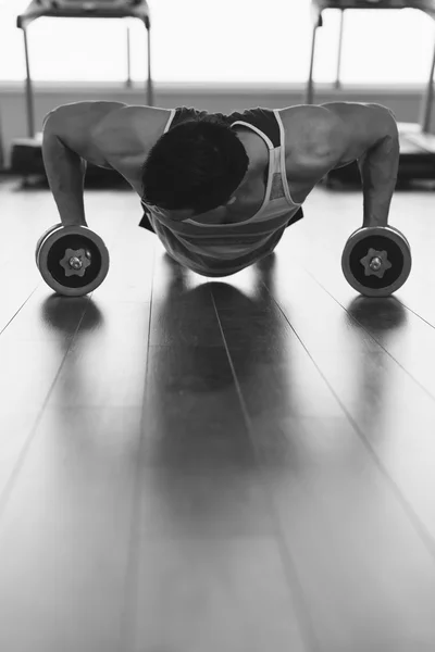 Homem musculoso a fazer flexões em halteres no ginásio. Poderoso masculino e — Fotografia de Stock