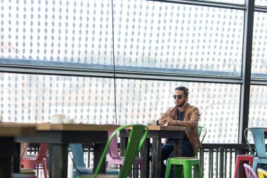 Genç adam onun smartphone kafede siting üzerinde tarama Internet