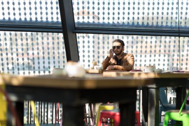 Mutlu hipster sandalyede oturan kafede akıllı telefon kullanma