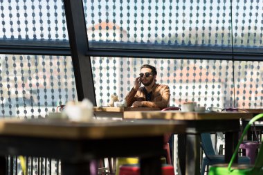 Mutlu hipster sandalyede oturan kafede akıllı telefon kullanma