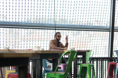 Genç adam onun smartphone kafede siting üzerinde tarama Internet