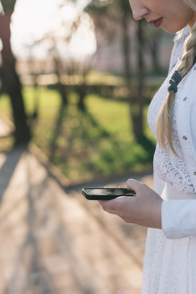 Chica con teléfono inteligente al aire libre en el parque. Primer plano de las manos femeninas a — Foto de Stock