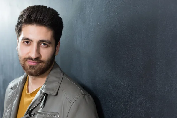 Handsome confident young man standing with folded arms against a — Stock Photo, Image