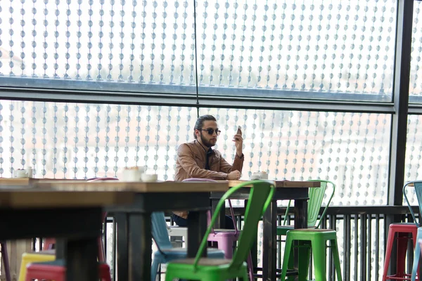 Νεαρός ξεφυλλίσματος Διαδικτύου σχετικά με την χωροθέτηση smartphone στο café — Φωτογραφία Αρχείου