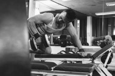 Spor salonunda dumbbells ile çalışma dışarı kaslı yakışıklı genç
