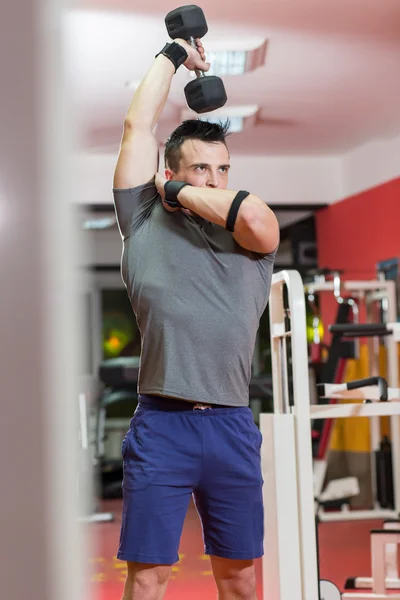 Muscular hombre levantando mancuerna en el gimnasio — Foto de Stock