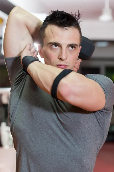 Muscular hombre levantando mancuerna en el gimnasio — Foto de Stock