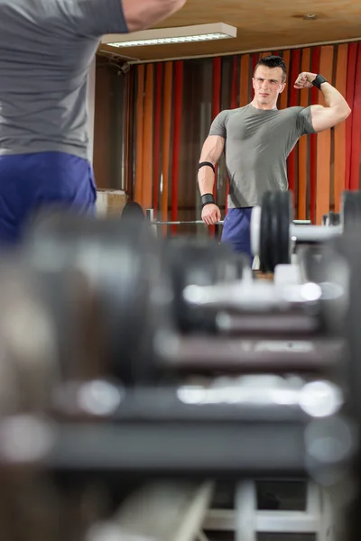 Hombre guapo levantando mancuerna en el gimnasio — Foto de Stock