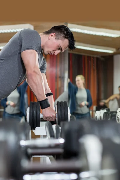 Hombre guapo levantando mancuerna en el gimnasio — Foto de Stock