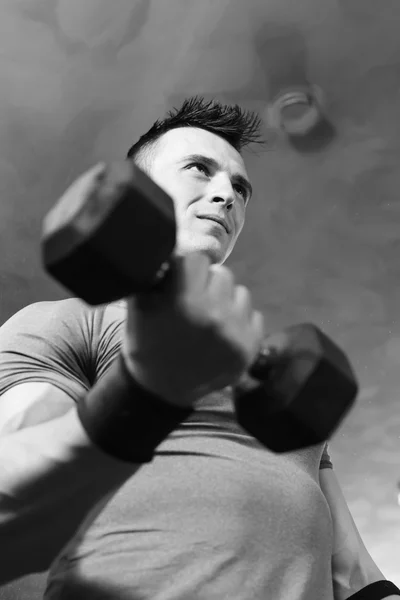 Man in sportswear lifting dumbbell at the gym — Stock Photo, Image