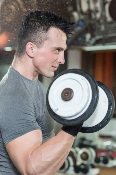 Hombre en ropa deportiva levantando mancuerna en el gimnasio — Foto de Stock