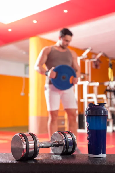 Proteína de suero, mancuerna y agitador de plástico en el suelo del gimnasio — Foto de Stock