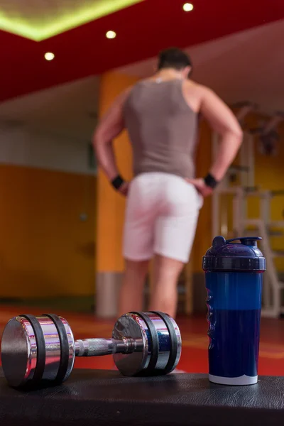 Proteína de suero, mancuerna y agitador de plástico en el suelo del gimnasio — Foto de Stock