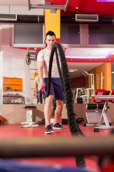 Lutando cordas homem no ginásio exercício físico corpo equipado — Fotografia de Stock