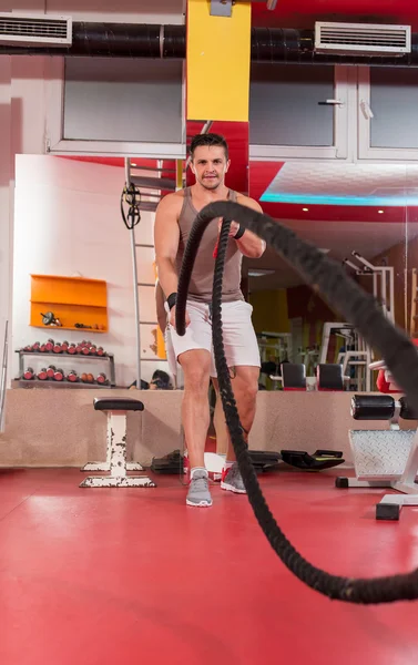 Lutando cordas homem no ginásio exercício físico corpo equipado — Fotografia de Stock