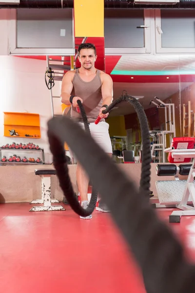 Hombre de las cuerdas de batalla en el ejercicio de gimnasio cuerpo ajustado ejercicio — Foto de Stock