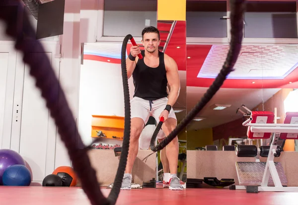 Hombre de las cuerdas de batalla en el ejercicio de gimnasio cuerpo ajustado ejercicio — Foto de Stock