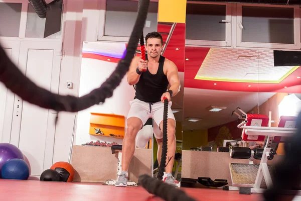 Hombre de las cuerdas de batalla en el ejercicio de gimnasio cuerpo ajustado ejercicio — Foto de Stock
