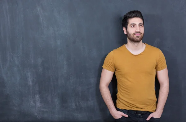 Attractive young man against blackboard. — Stock Photo, Image