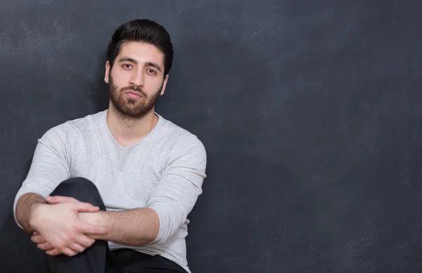 A young man with a beard on a chalkboard background with the emo — Stock Photo, Image