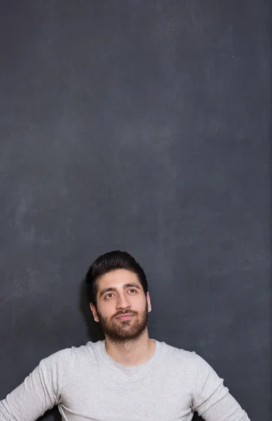 A young man with a beard on a chalkboard background with the emo — Stock Photo, Image