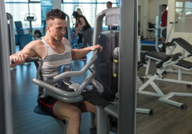 Spor salonunda ağırlık makine kullanan adam