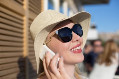 Onun bir telefon tutarak şapkalı güzel bir genç kadının detay 