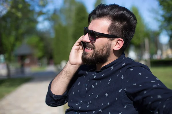 Hombre feliz usando un teléfono inteligente al aire libre con un fondo verde — Foto de Stock