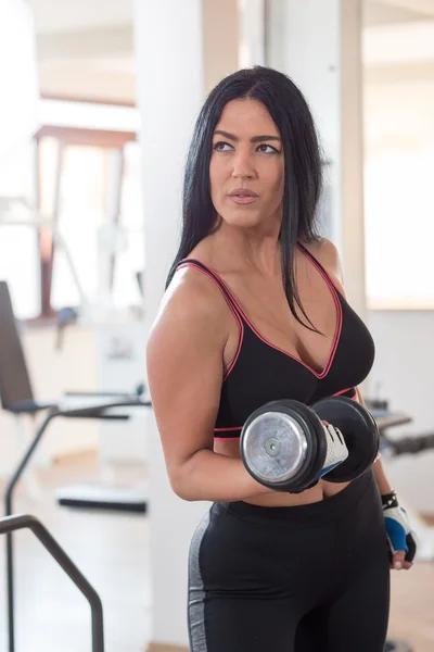 Vrouw gewicht tillen met fitnessapparatuur in de fitnessclub, por — Stockfoto