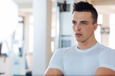 Sportif adam bir spor salonunda dinleniyor. Genç bir kas portresi sportif