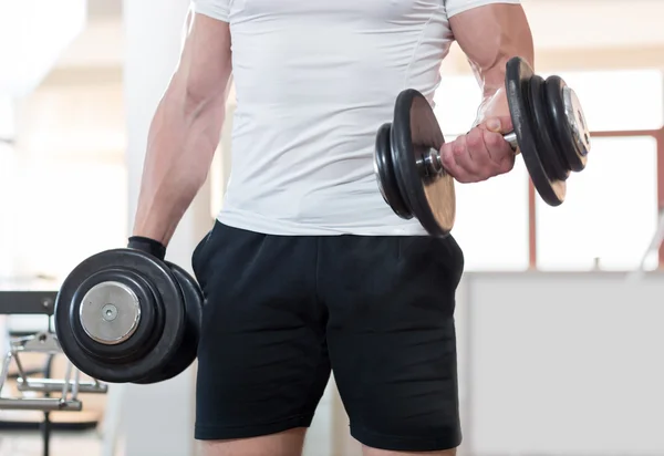 Muscular fisiculturista cara fazendo exercícios com halteres no ginásio — Fotografia de Stock