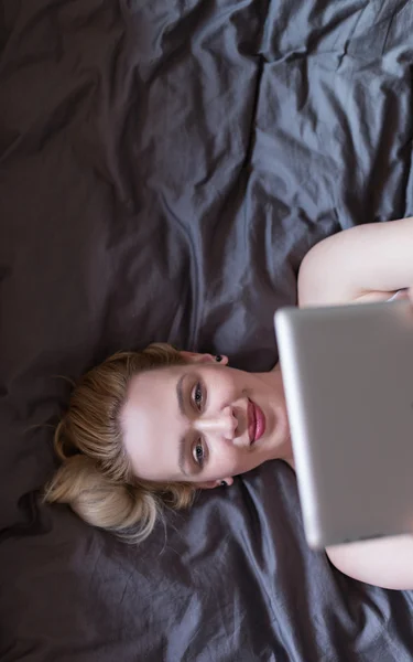 Woman using tablet on her bed — Stock Photo, Image