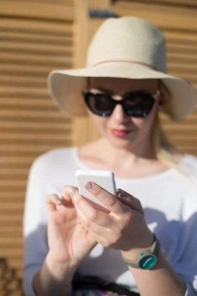 Detalle de una hermosa joven con sombrero sosteniendo un teléfono en su — Foto de Stock