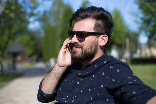 Hombre feliz usando un teléfono inteligente al aire libre con un fondo verde — Foto de Stock