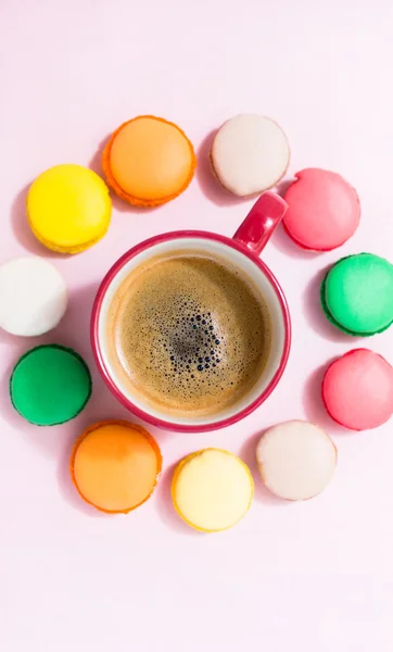 Kaffeetasse und bunte Makronen auf pastellfarbenem Hintergrund, Draufsicht — Stockfoto