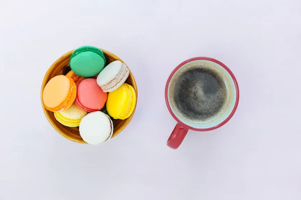 Coffe hrnek a barevné makronky na pozadí pastelové, pohled shora — Stock fotografie