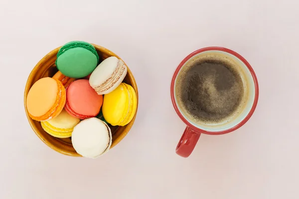 Kaffeetasse und bunte Makronen auf pastellfarbenem Hintergrund, Draufsicht — Stockfoto