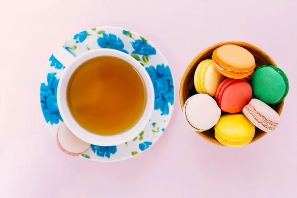 Colorful macaroons with cup of tea on pastel background — Stock Photo, Image