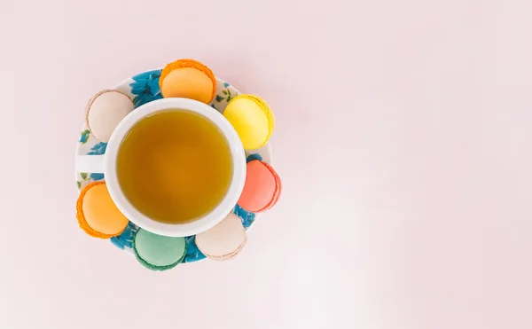 Barevné makaróny s šálkem čaje na pastelové pozadí — Stock fotografie