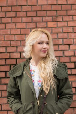 Bir tuğla duvara poz güzel sarışın bir kadın portresi