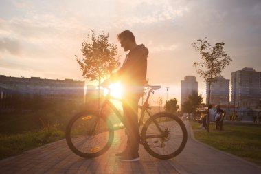 Genç yakışıklı hipster adam Bisiklet sunset bulvarında poz