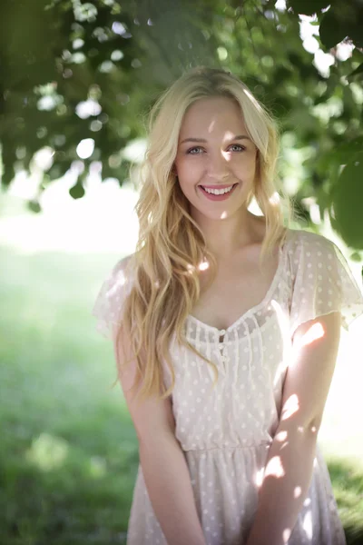 Krásná blonďatá dívka na zelené louce s květinami. venkovské scény — Stock fotografie