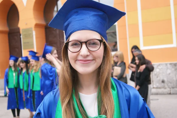 Graduate students wearing graduation hat and gown, outdoors