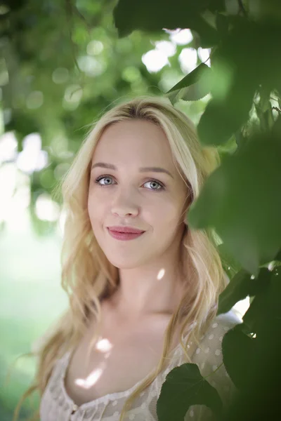 Beautiful blond girl on green field with flowers. Rural scene Royalty Free Stock Images