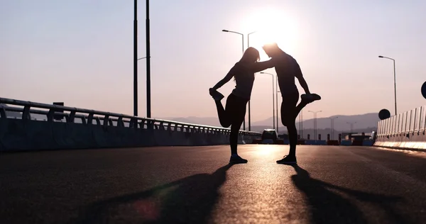 Silhouetten eines Paares, das sich bei Sonnenuntergang dehnt — Stockfoto