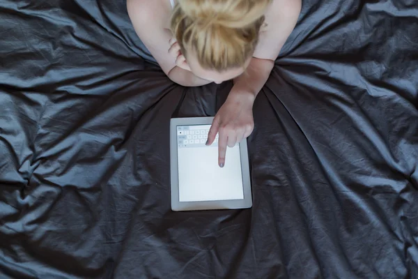 Kobieta stosująca tabletkę w łóżku — Zdjęcie stockowe