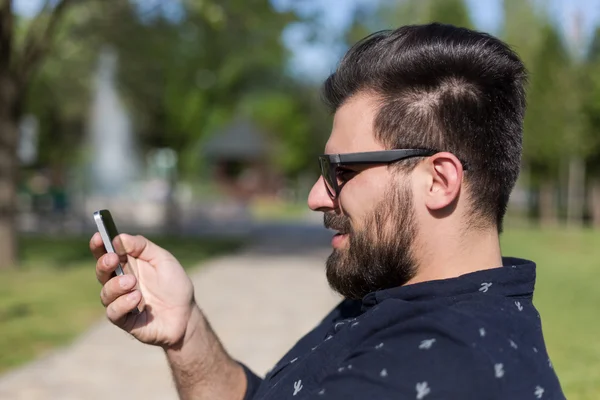 Hombre barbudo joven usando teléfono inteligente — Foto de Stock