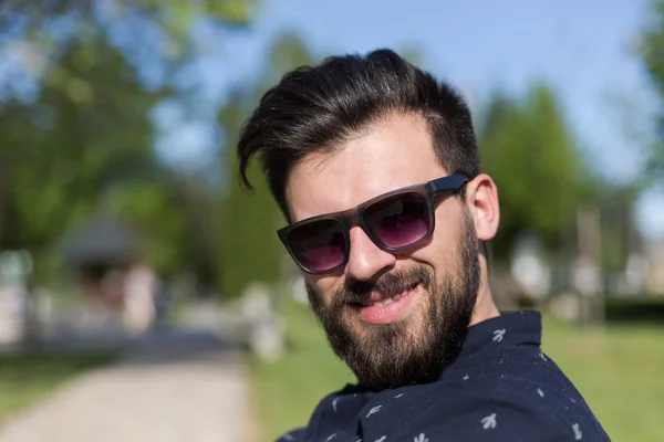 Hombre joven relajándose en el banco del parque — Foto de Stock